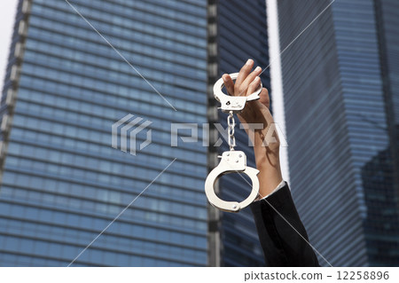 Hands holding up handcuffs outside 12258896