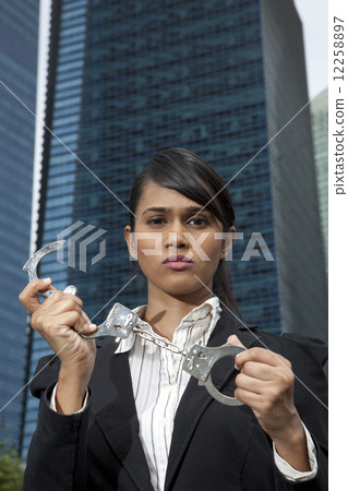 Business woman holding handcuffs outside 12258897