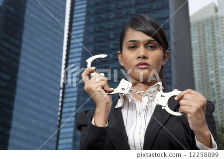 Business woman holding handcuffs outside 12258899