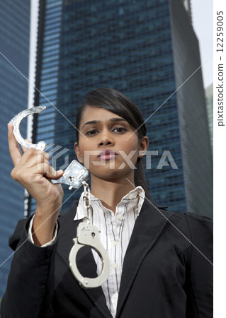 Business woman holding handcuffs outside  12259005