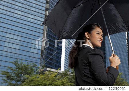 Businesswoman holding umbrella outdoors 12259061