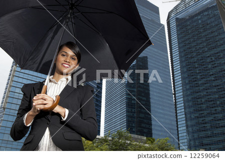 Businesswoman holding umbrella outdoors 12259064