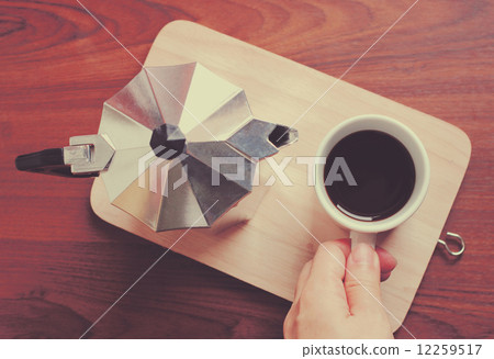 Hand holding coffee cup and moka pot with retro filter effect 12259517