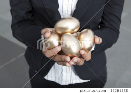 close-up of hands holding gold eggs outdoors 12261388