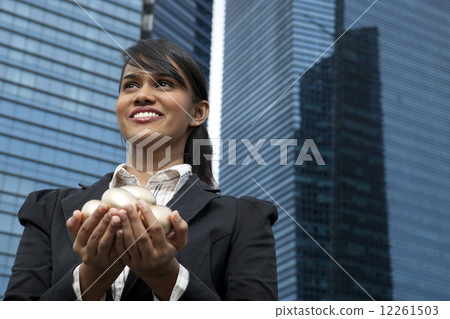 Businesswoman holding gold eggs outdoors 12261503