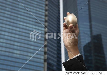 Close-up of hand holding gold egg outdoors 12261505