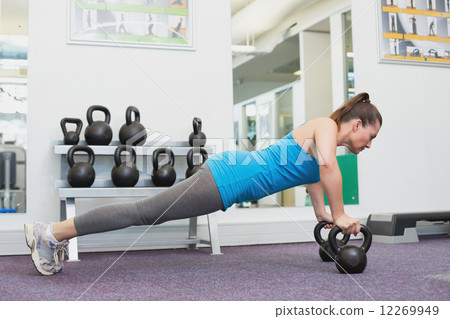 Fit brunette working out with kettlebell  12269949