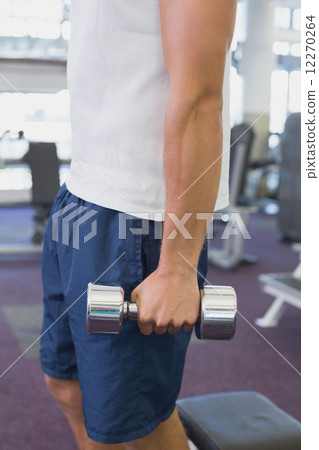 Fit man holding heavy dumbbell 12270264