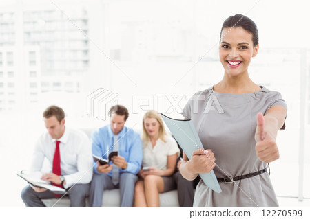 Businesswoman gesturing thumbs up against people waiting for interview Businesswoman gesturing thumbs up against people waiting for interview 12270599