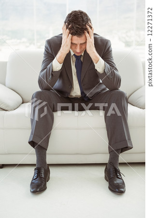 Stock Photo: Worried businessman with head in hands sitting on couch