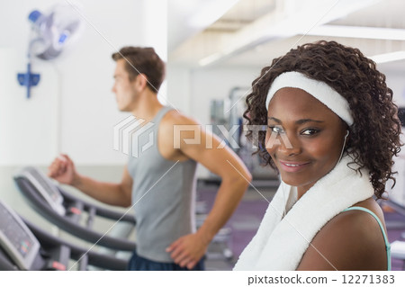 Fit woman smiling at camera on treadmill 12271383