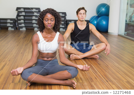 Fit couple sitting in lotus pose in fitness studio Fit couple sitting in lotus pose in fitness studio 12271468
