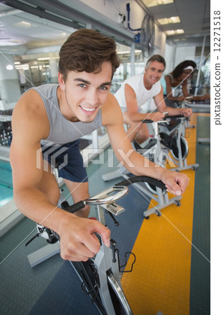 Three fit people working out on exercise bikes Three fit people working out on exercise bikes 12271518