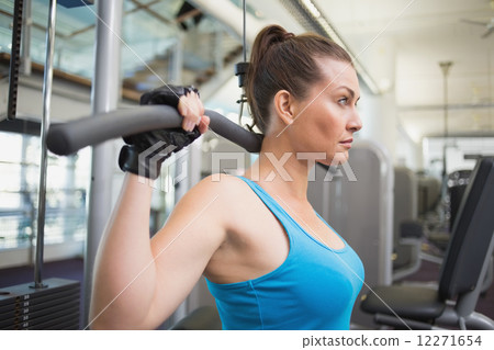 Fit brunette using weights machine for arms 12271654