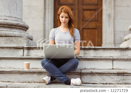 Woman with disposable cup using laptop 12271729