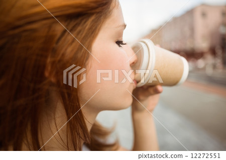 Pretty redhead drinking from disposable cup 12272551