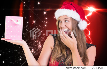 Composite image of festive blonde holding a gift bag 12273509