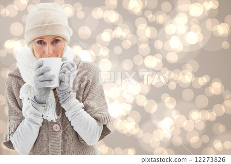 Composite image of woman in warm clothing holding mugs 12273826
