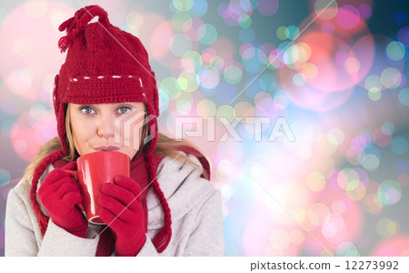 Composite image of happy blonde in winter clothes holding mug 12273992