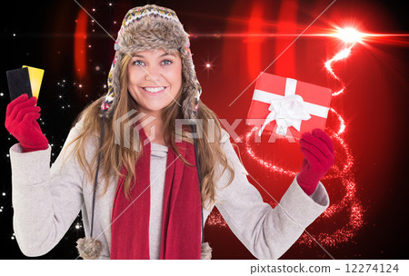 Composite image of happy blonde in winter clothes holding gifts 12274124