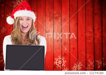 Composite image of festive blonde showing a laptop 12274180