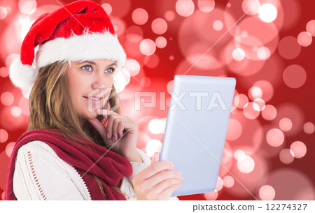 Composite image of festive blonde looking at tablet pc 12274327