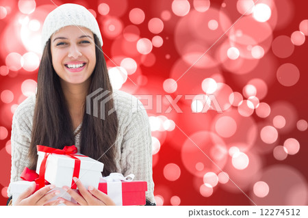 Composite image of festive brunette holding gifts Composite image of festive brunette holding gifts 12274512