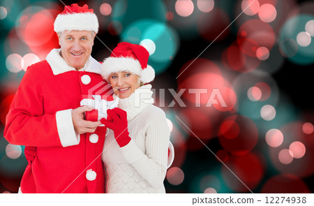 Composite image of festive mature couple holding gift 12274938