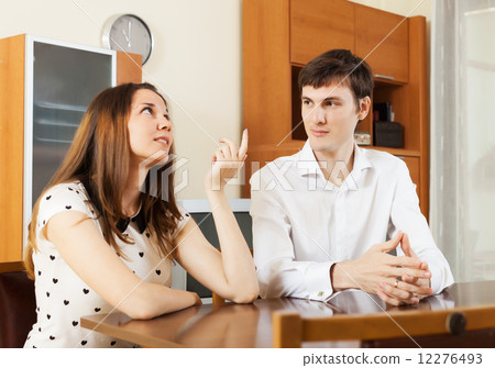 young couple having serious talking at table 12276493