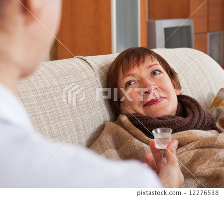 nurse giving medicament to mature woman 12276538
