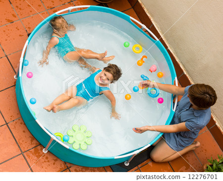 Female baby-sitter with little girls at pool Female baby-sitter with little girls at pool 12276701