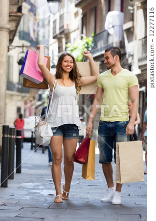 Smiling young pair with shopping bags at city 12277116