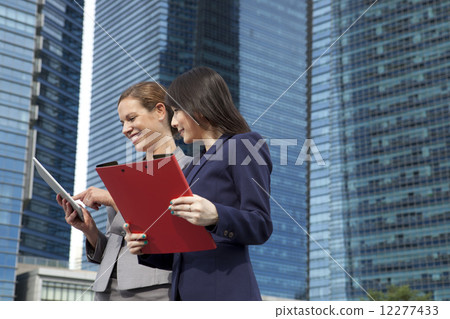 Businesswomen looking at tablet outside Businesswomen looking at tablet outside 12277433