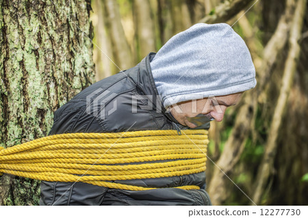 Man with tape on mouth tied to the tree Man with tape on mouth tied to the tree 12277730