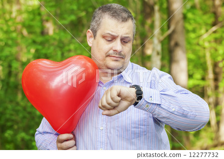 Man with red balloon staring at the clock  12277732