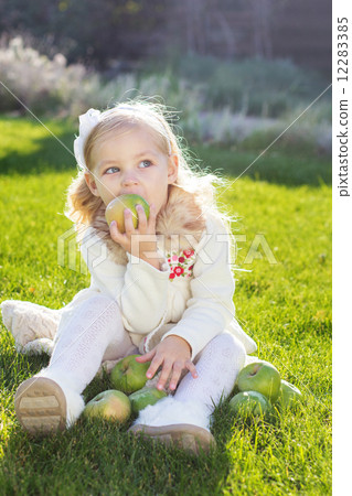 Child with green apples sitting on grass Child with green apples sitting on grass 12283385