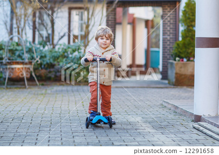 Little toddler boy riding and his scooter bicycle in summer 12291658