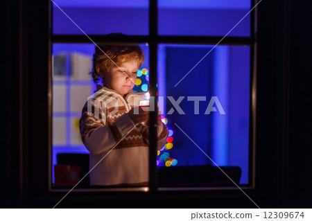 Sweet child standing by window at Christmas time and holding can 12309674