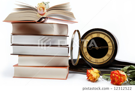 A stack of books and antique clock on a white background. A stack of books and antique clock on a white background. 12312522