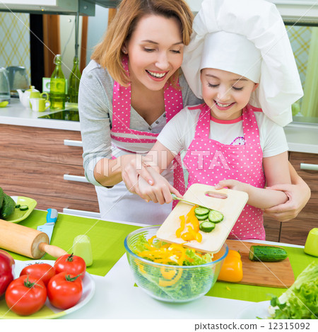 Smiling mother and daughter cooking a salad. 12315092