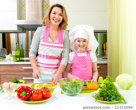 Smiling mother and daughter cooking a salad. 12315094