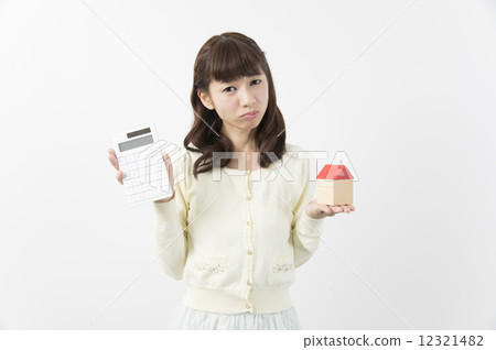 A young woman holding a calculator and a house, worried about her future plans A young woman holding a calculator and a house, worried about her future plans 12321482