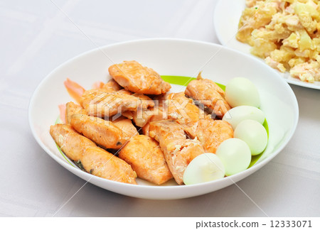 Pieces of baked red fish and cooked quail eggs on white plate. 12333071