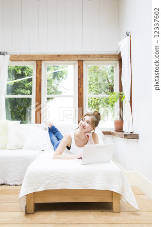 一位躺下來操作個人電腦的女士 一位躺下來操作個人電腦的女士 12337602