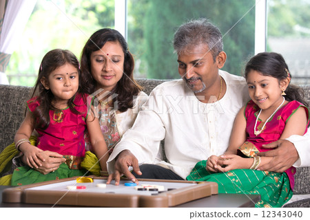 Indian family playing carrom game at home. Parents and children 12343040