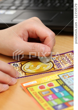 Woman scratching lottery ticket. It's published by BC Lottery Corporation  12359579