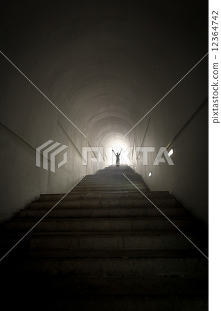 person standing in the end of tunnel at light beam with hands ra person standing in the end of tunnel at light beam with hands ra 12364742