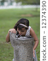 Young Indian Girl drinking from water cooler in park 12374390