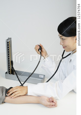Female doctor measuring blood pressure gauge 12374764
