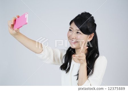 A young woman taking self-taking at a smartphone A young woman taking self-taking at a smartphone 12375889